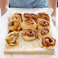 Tray of cinnamon scrolls with icing on baking paper, made using the Starter Kit