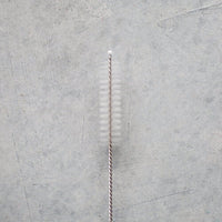 Straw Cleaning Brush laid flat, showing its long narrow bristle head