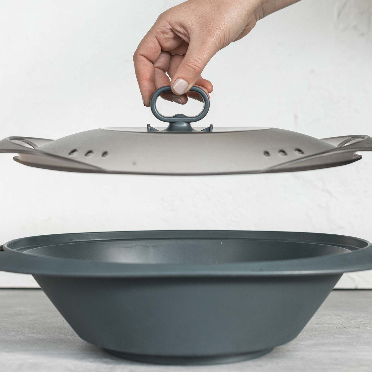 Hand gripping the Suction Handle to lift the Varoma lid clear of the tray