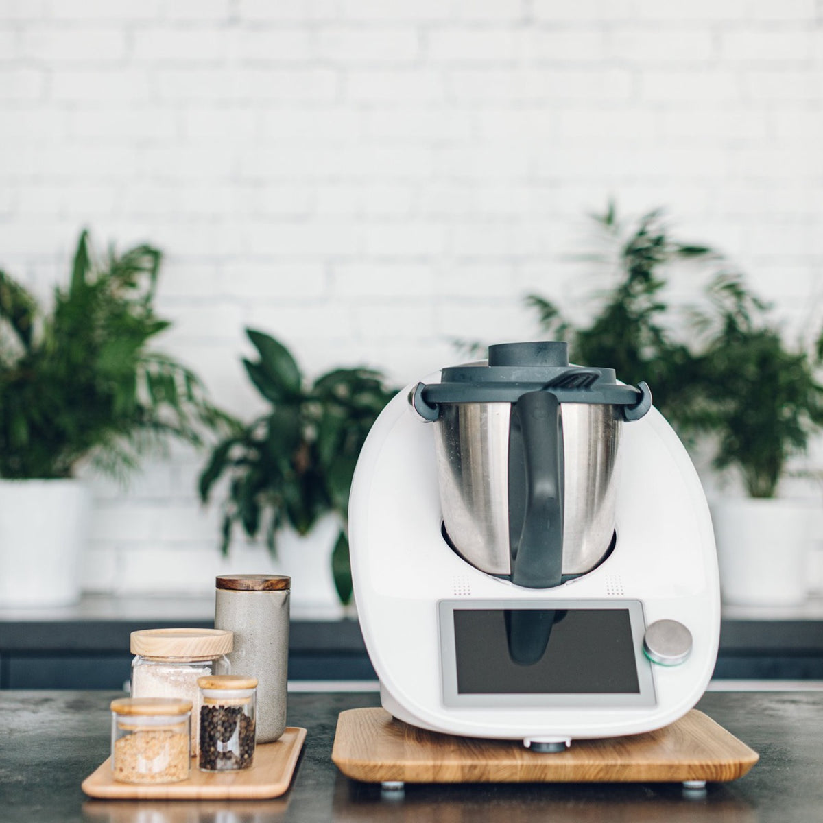 Thermomix on the Thermo Deluxe Slide Board in a styled kitchen with plants and storage jars