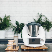 Thermomix on the Thermo Deluxe Slide Board in a styled kitchen with plants and storage jars