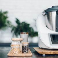 Thermomix on the Thermo Deluxe Slide Board beside glass storage jars and greenery