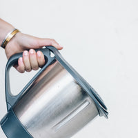 Hand tilting the Thermomix bowl with the Thermo Lid Strainer fitted, ready to pour