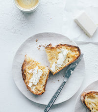 Toasted sandwich cut in half on a plate with a block of vegan cheese alongside, from Thermo Plant-Based