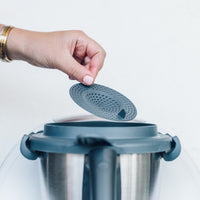 Hand lowering the Thermo Splash Cap onto a Thermomix mixing bowl