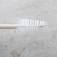 TM Blade Brush laid flat showing its slim handle and narrow brush head