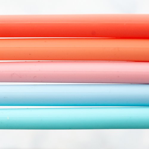 Close-up of Wide Reusable Silicone Straws in coral, pink and blue lined up together