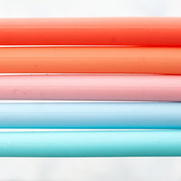 Close-up of Wide Reusable Silicone Straws in coral, pink and blue lined up together