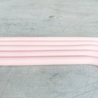 Four pink Wide Reusable Silicone Straws laid parallel on a grey surface, showing their bend