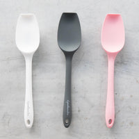 Three Slow Cooker Spatulas laid side by side in cream, charcoal and pink